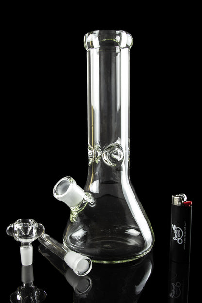 Glass bong with removable downstem and bowl, positioned next to a lighter on a reflective black surface.