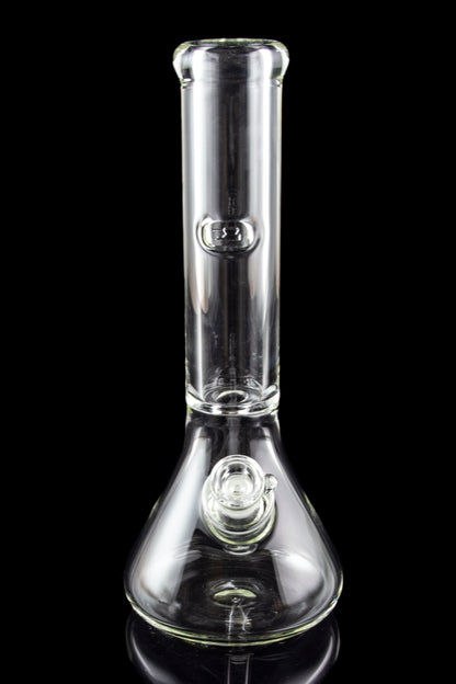 Clear glass water pipe (bong) with a flared base, reflecting on a dark surface.