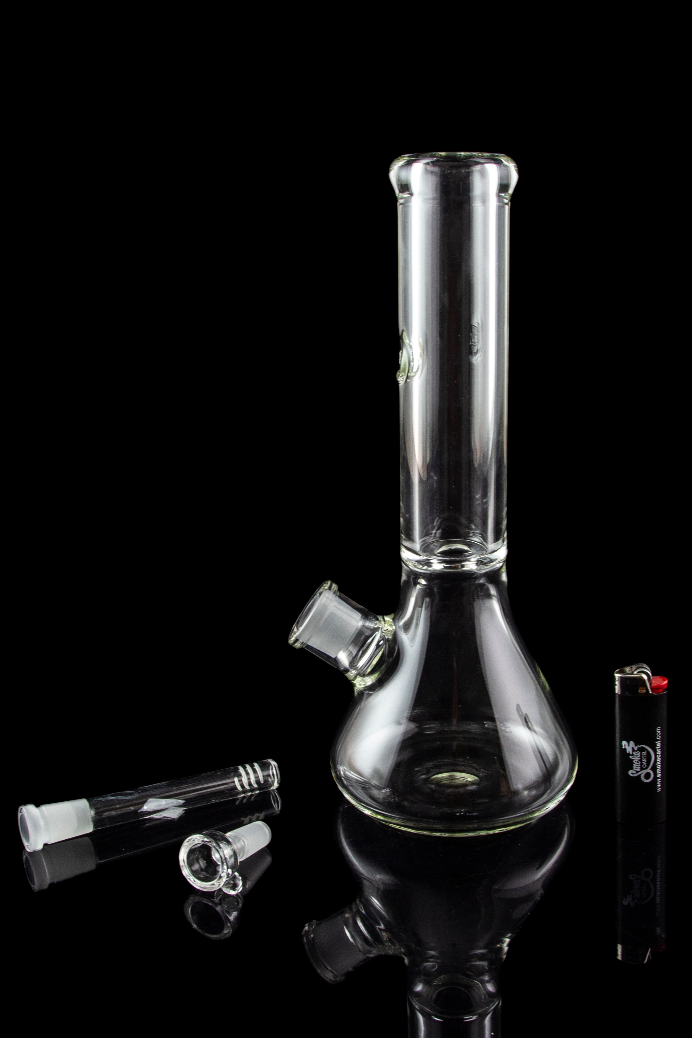 Glass bong and accessories on a reflective surface.