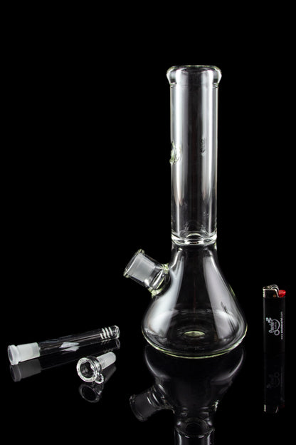 Glass bong and accessories on a reflective surface.