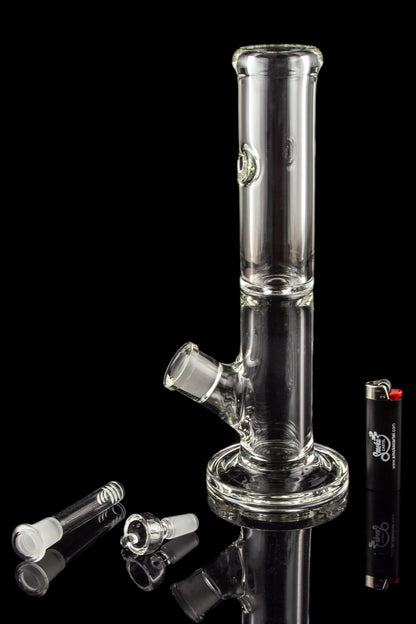 Clear glass water pipe (bong) with detached glass bowls and a lighter on a reflective surface.