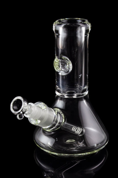 Clear glass bong with ice catcher, reflecting on a black surface.