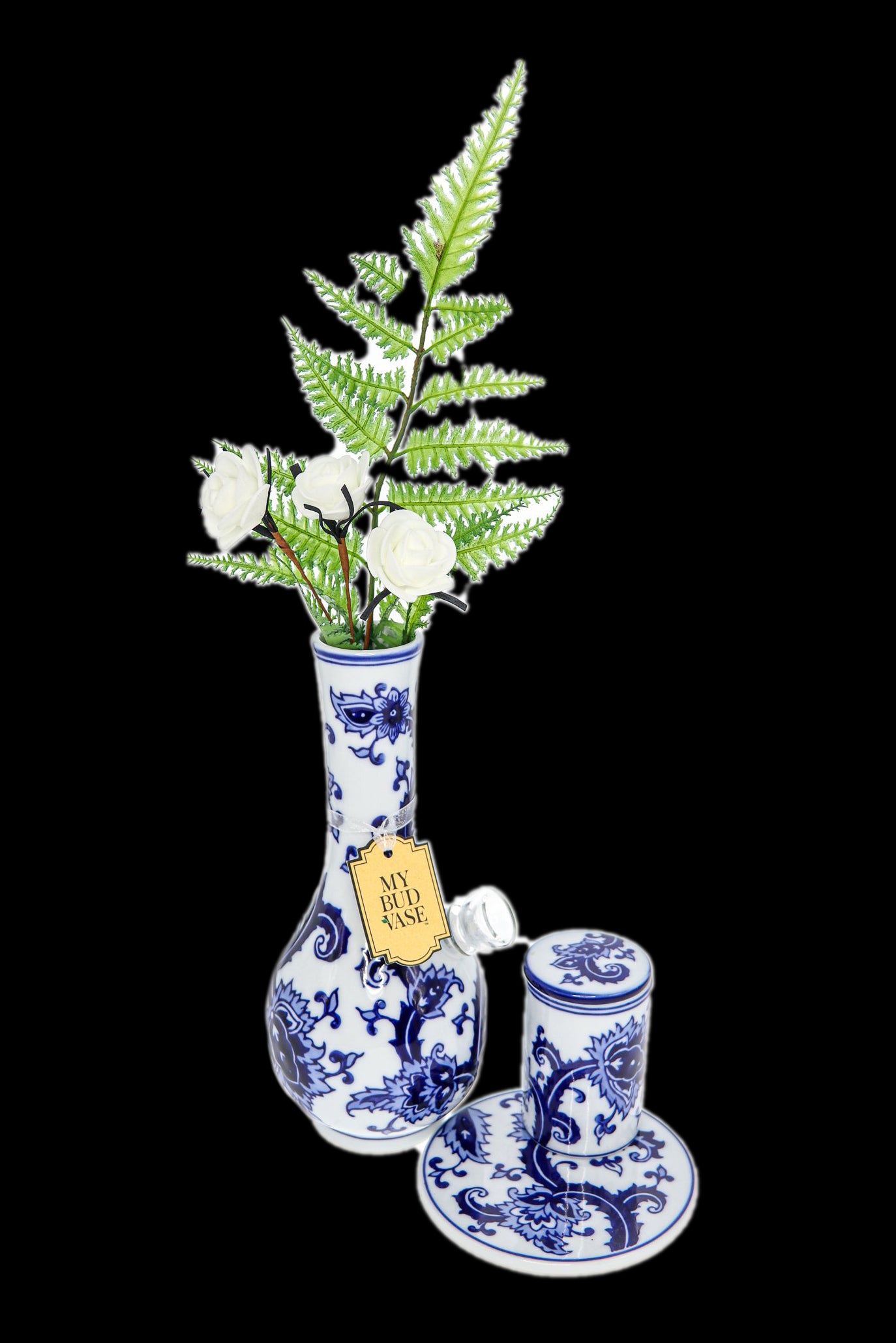 Blue and white porcelain cannabis vase with ferns and a matching jar and saucer set, isolated on a black background.