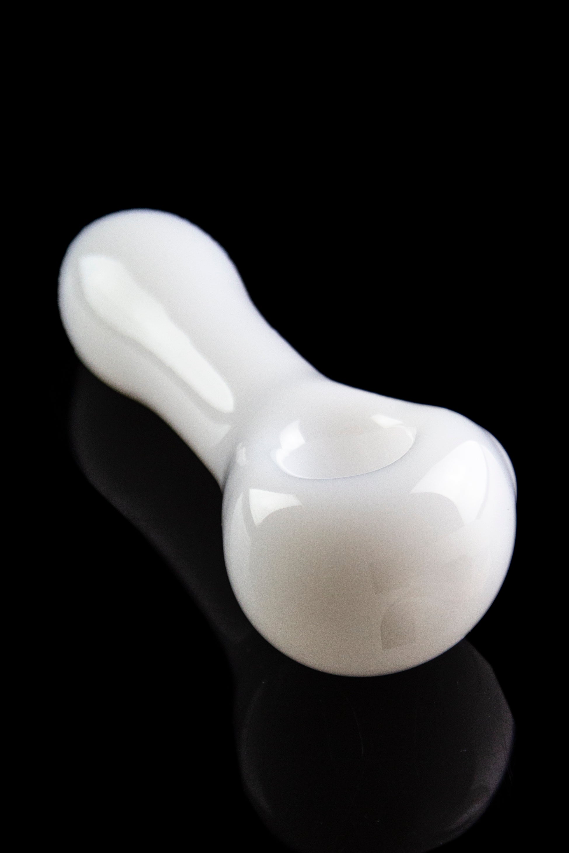 White glass pipe with a smooth, curved design, reflecting on a black surface.