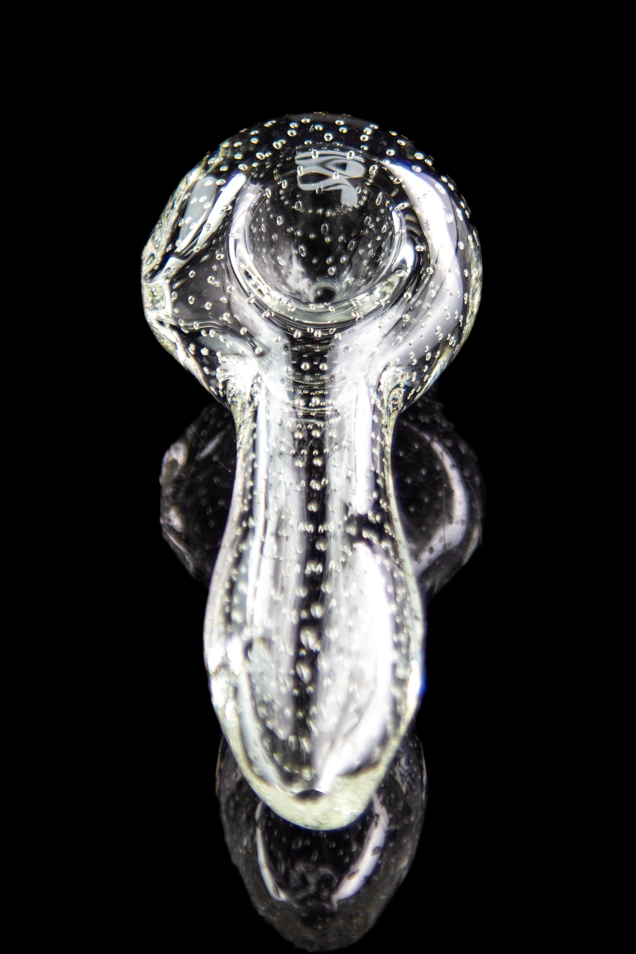 Clear glass bubbler pipe with speckled pattern, reflecting on a dark surface.