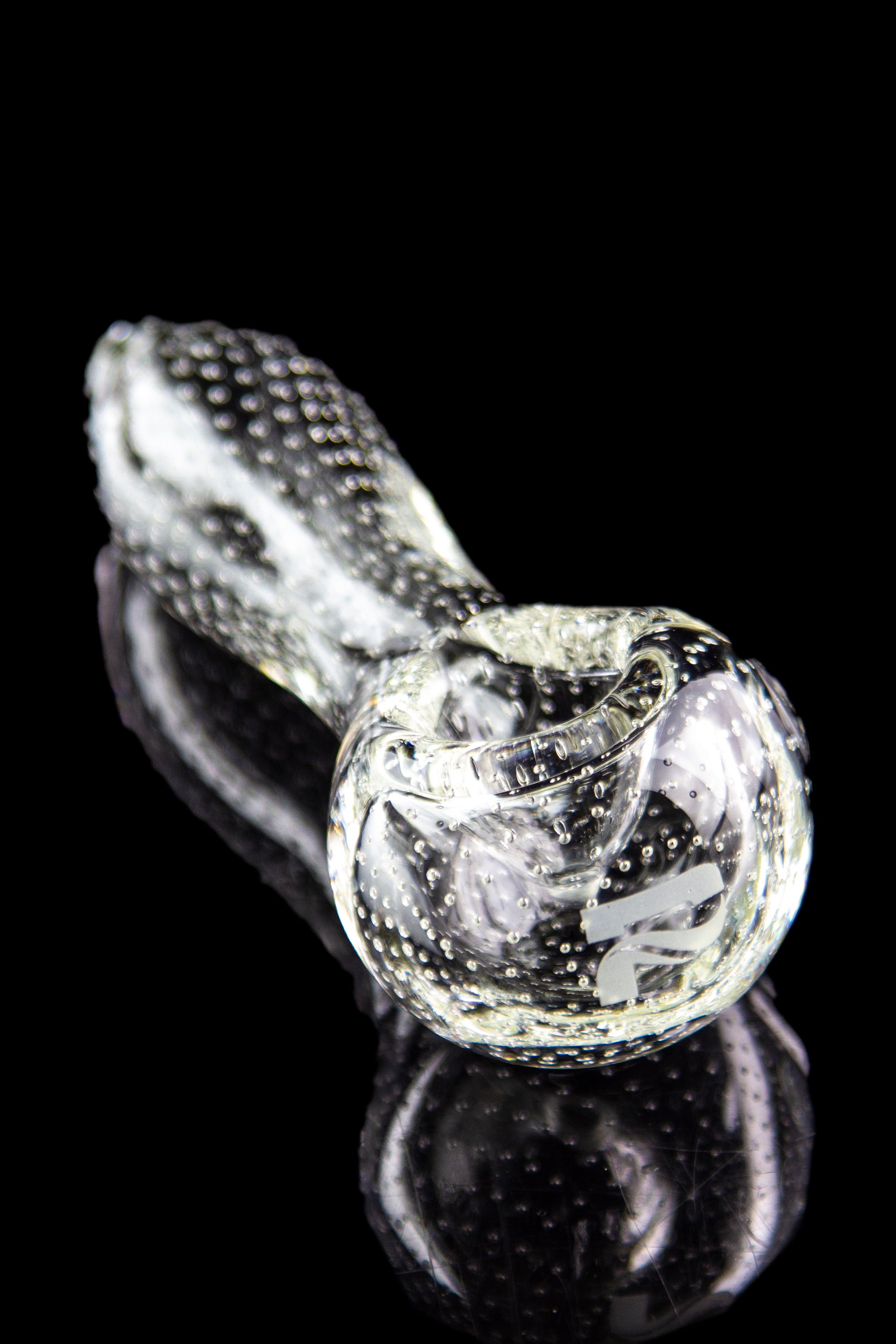 Clear glass pipe with textured surface and reflective black background.