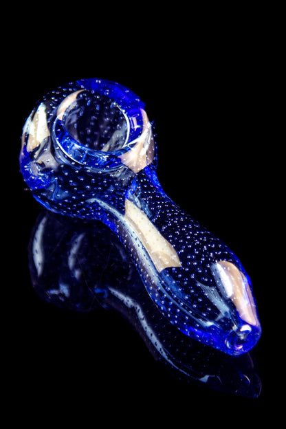 A side view of the Pulsar Bubble Matrix Spoon Pipe, showing a blue glass pipe with a speckled pattern against a black background.