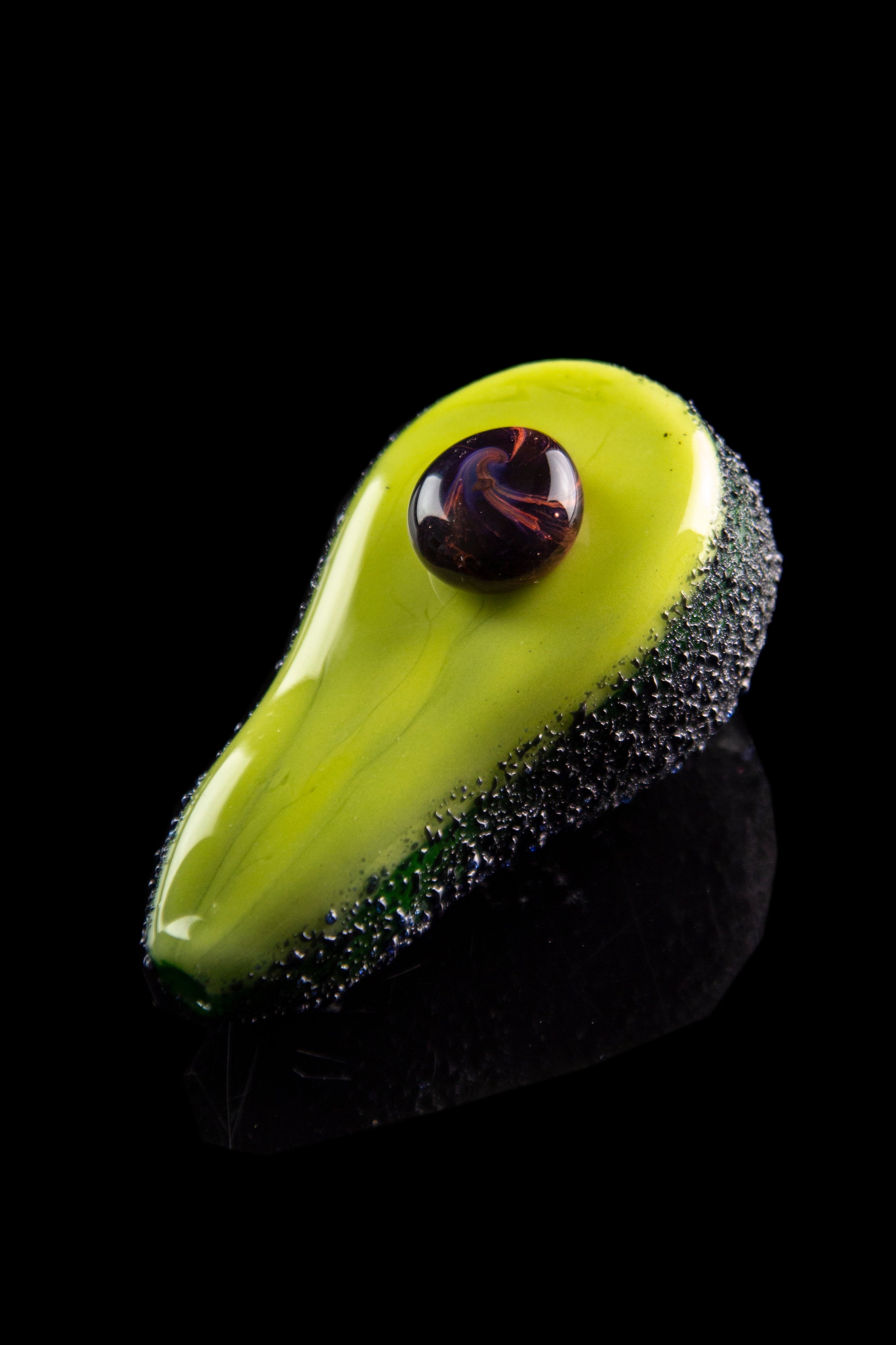 Green glass cannabis oil dab nail with dark speckles, isolated on black.