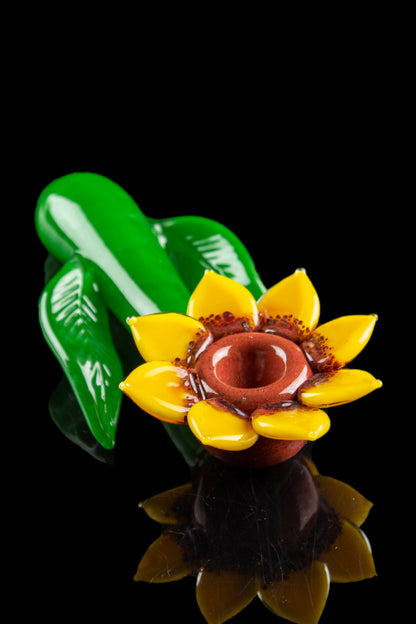 Glass sunflower pipe with green leaf base, studio shot on black background.