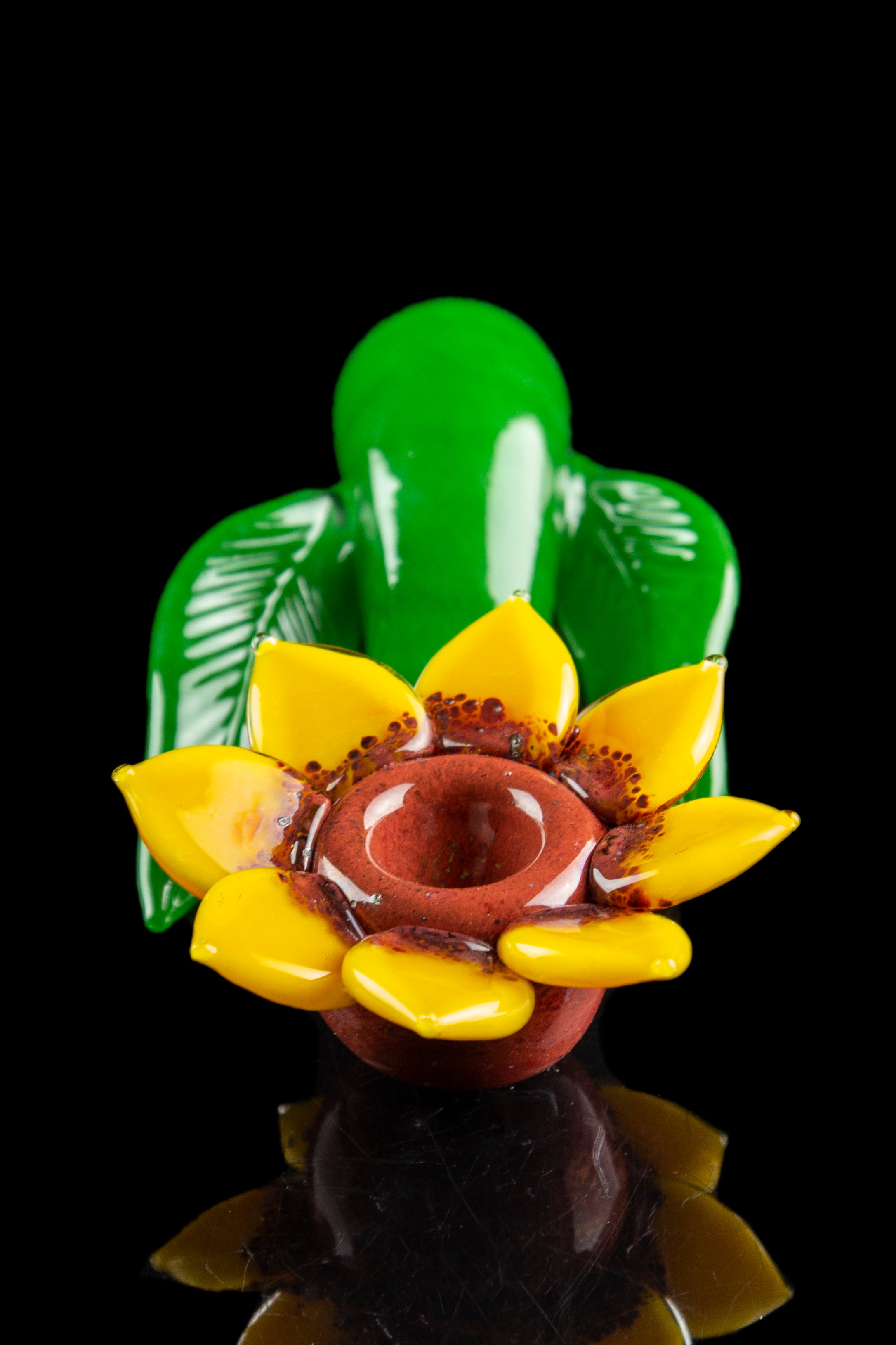 A vibrant glass sculpture resembling a lotus flower with a built-in bowl, set against a black background.