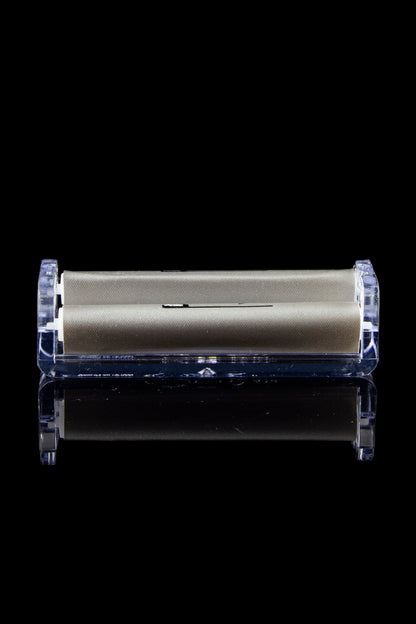 Sleek gold cannabis storage container encased in clear acrylic, with a mirrored reflection on a black surface.