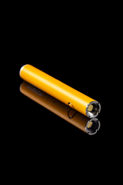 Golden cannabis oil vape cartridge with 510 thread on reflective black surface.