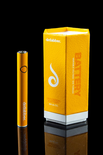 Gold Dr. Dabber battery and packaging on a reflective black surface.