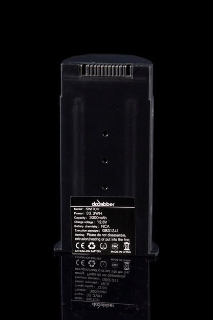 Close-up of a black “Droolubber Switch” portable power bank with technical specifications and warning labels, likely used for a cannabis vaporization device.
