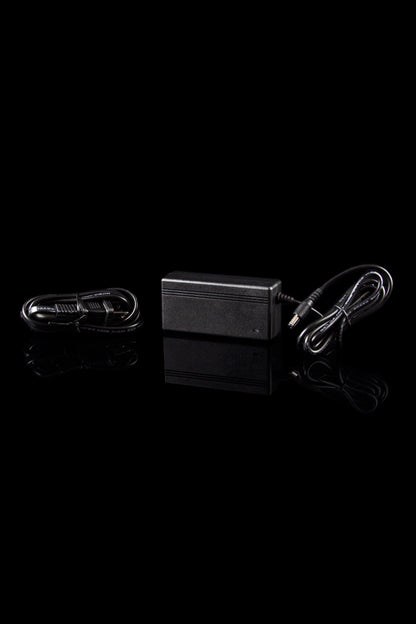 Black cannabis oil vaporizer pen charging kit with USB adapter and cord, studio shot.