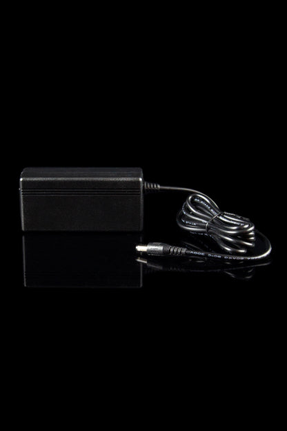 Side view of the black Dr. Dabber SWITCH Replacement Charging Cable and Adapter with coiled cord and connector on a reflective black surface