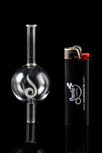 Glass oil rig with intricate design next to a lighter, reflecting on a glossy black surface.