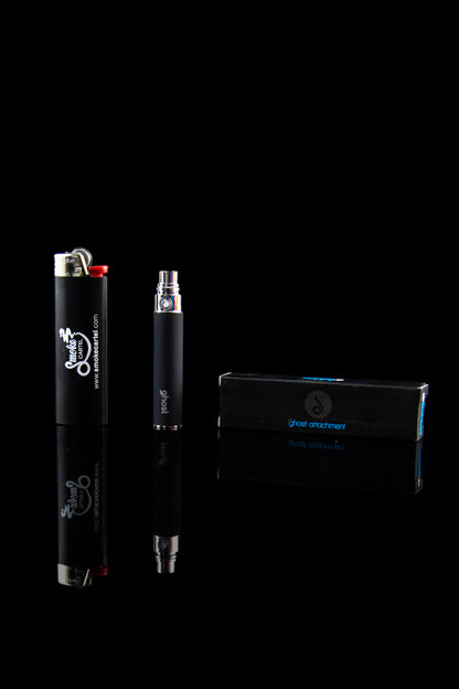 Black cannabis oil vaporizer pen and packaging on a reflective surface.