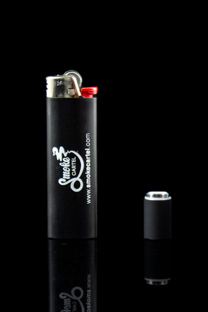 Black lighter with "Smoke Cartel" branding and disassembled components reflecting on a dark surface.