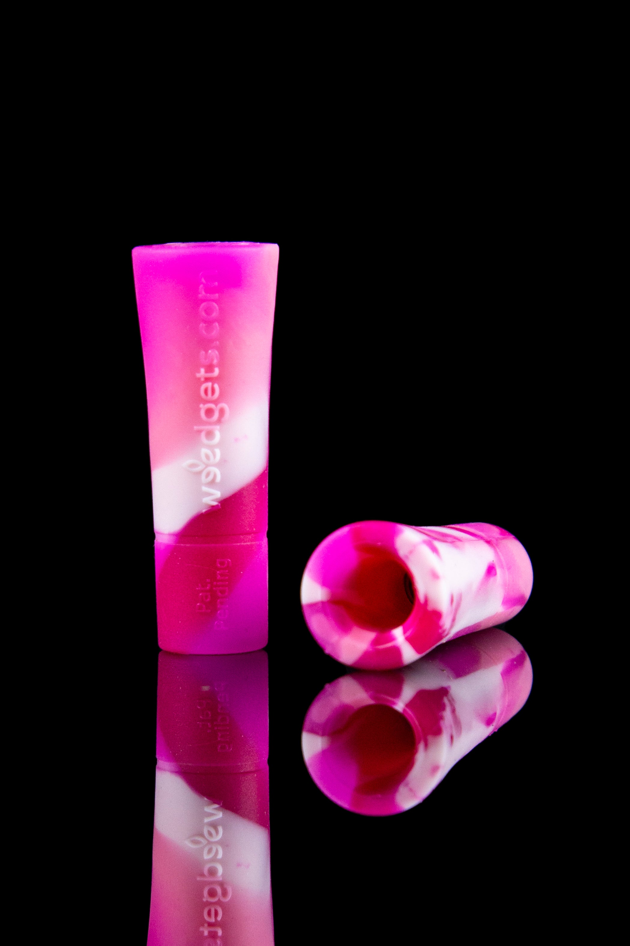 Pink and white glass cannabis filter tips displayed on a reflective surface.