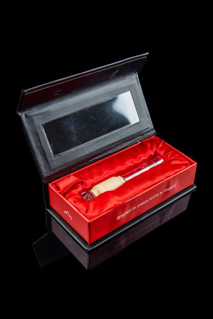 Luxury cannabis pipe presentation box with gold-toned pipe inside.
