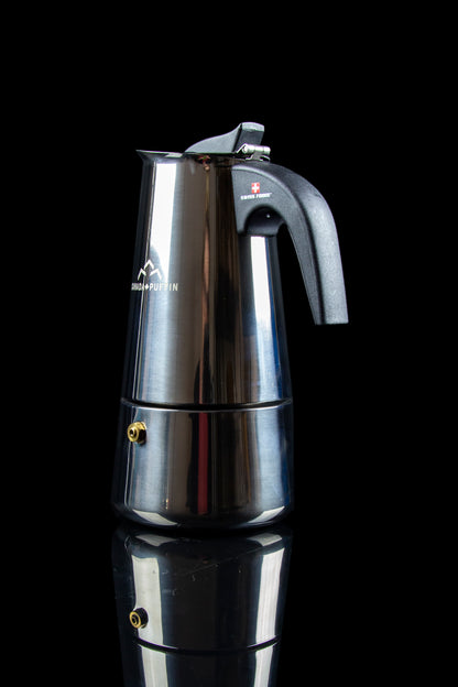 Silver stovetop espresso maker with cannabis leaf branding, studio shot.
