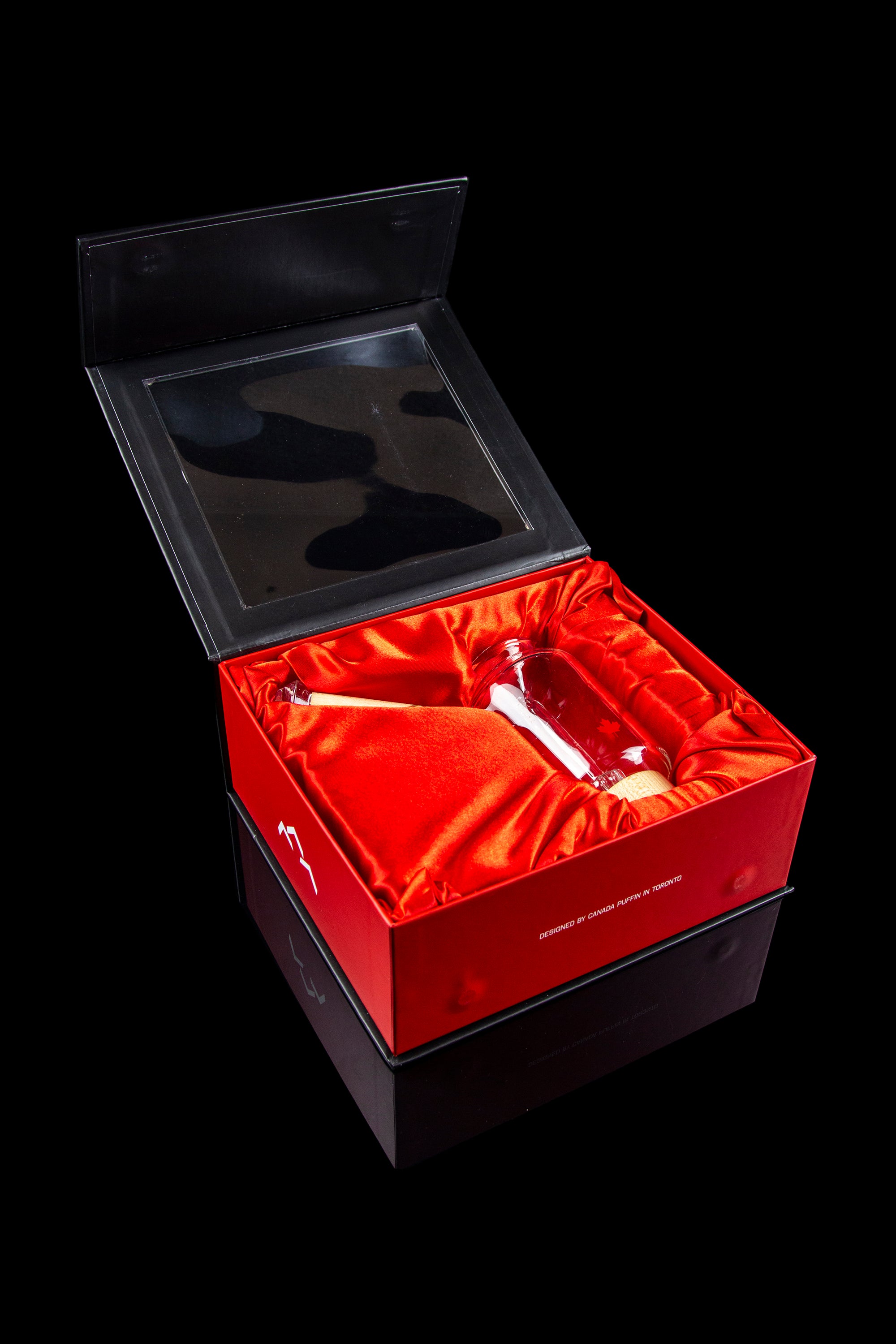 Open red gift box containing a glass cannabis pipe and accessories, with branding text "Designed by Canada Puffin in Toronto."
