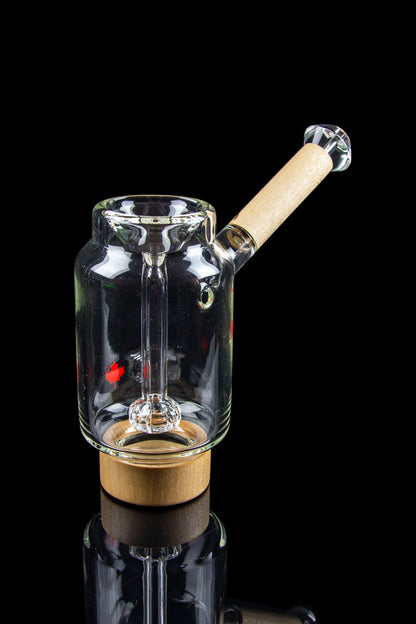 Clear glass water pipe with a wooden base and mouthpiece, reflecting on a glossy black surface.