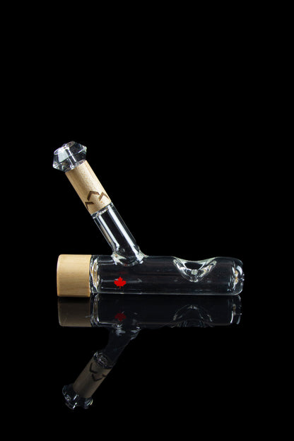 Clear glass water pipe with a maple leaf logo, reflecting on a black surface.