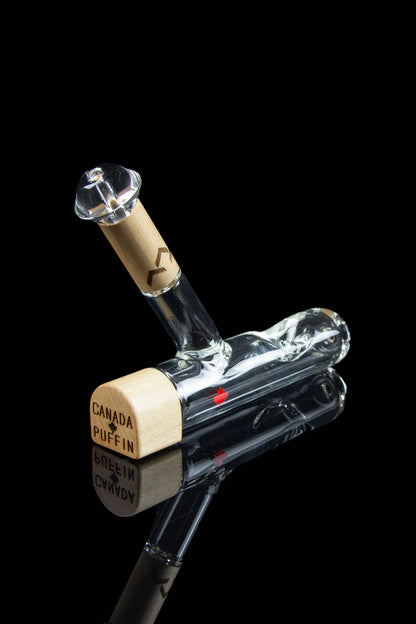 Glass bubbler with wooden accents and “Canada Puffin” text, reflected on a dark surface.