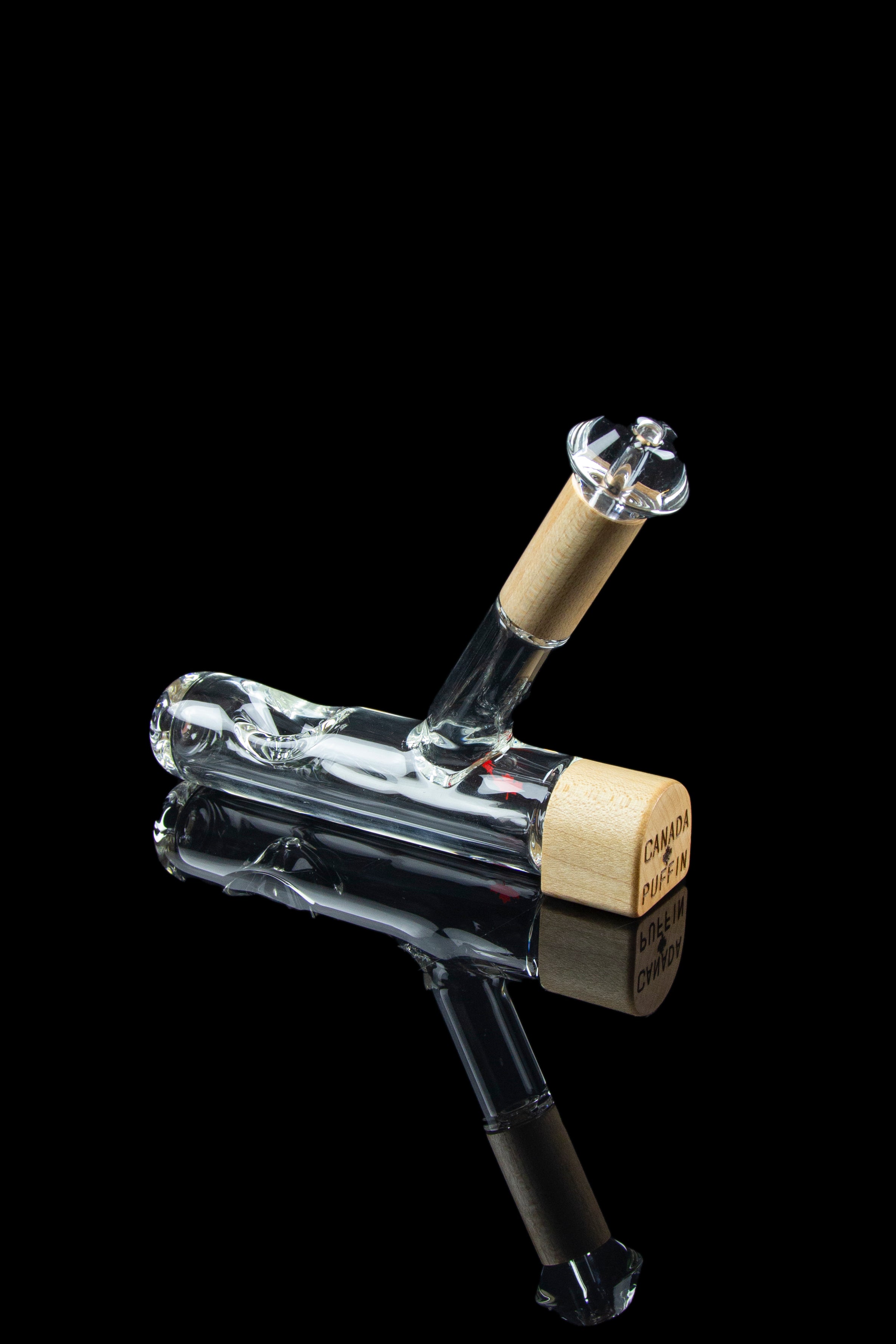 Clear glass water pipe with a textured gold mouthpiece, reflecting on a glossy black surface.