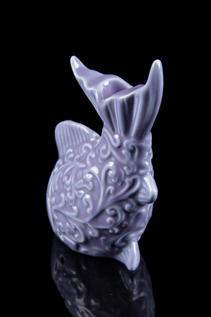 Lavender ceramic water pipe shaped like a bunny with ornate detailing, reflecting on a dark surface.