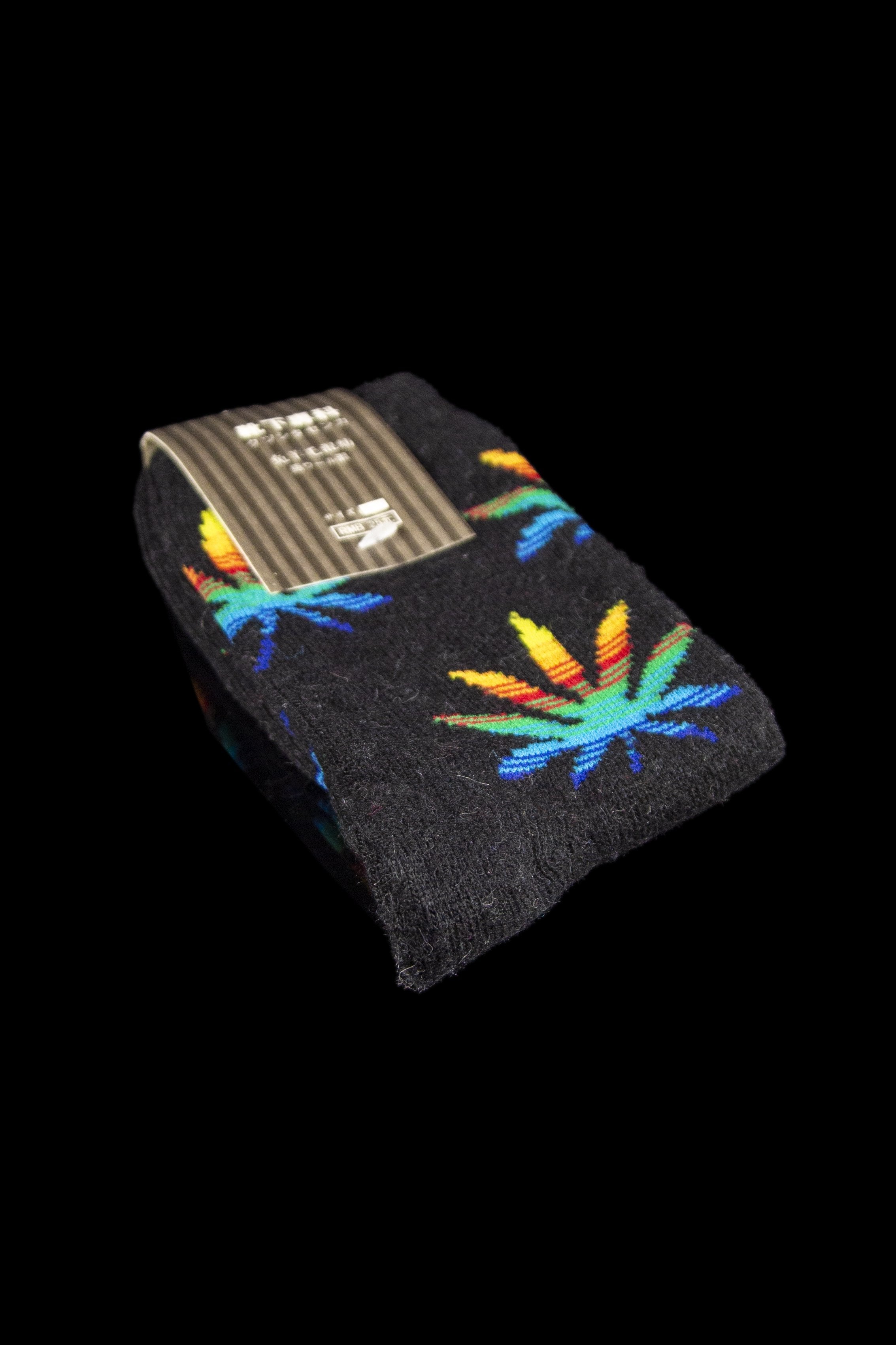 Black socks with a colorful cannabis leaf pattern, displayed against a black background.