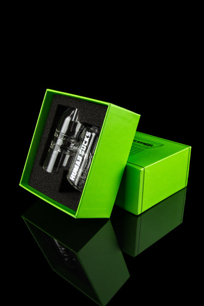 A clear glass cannabis water pipe with “HUMAN SUCKS” printed on it, presented in a bright green gift box with a reflective surface.