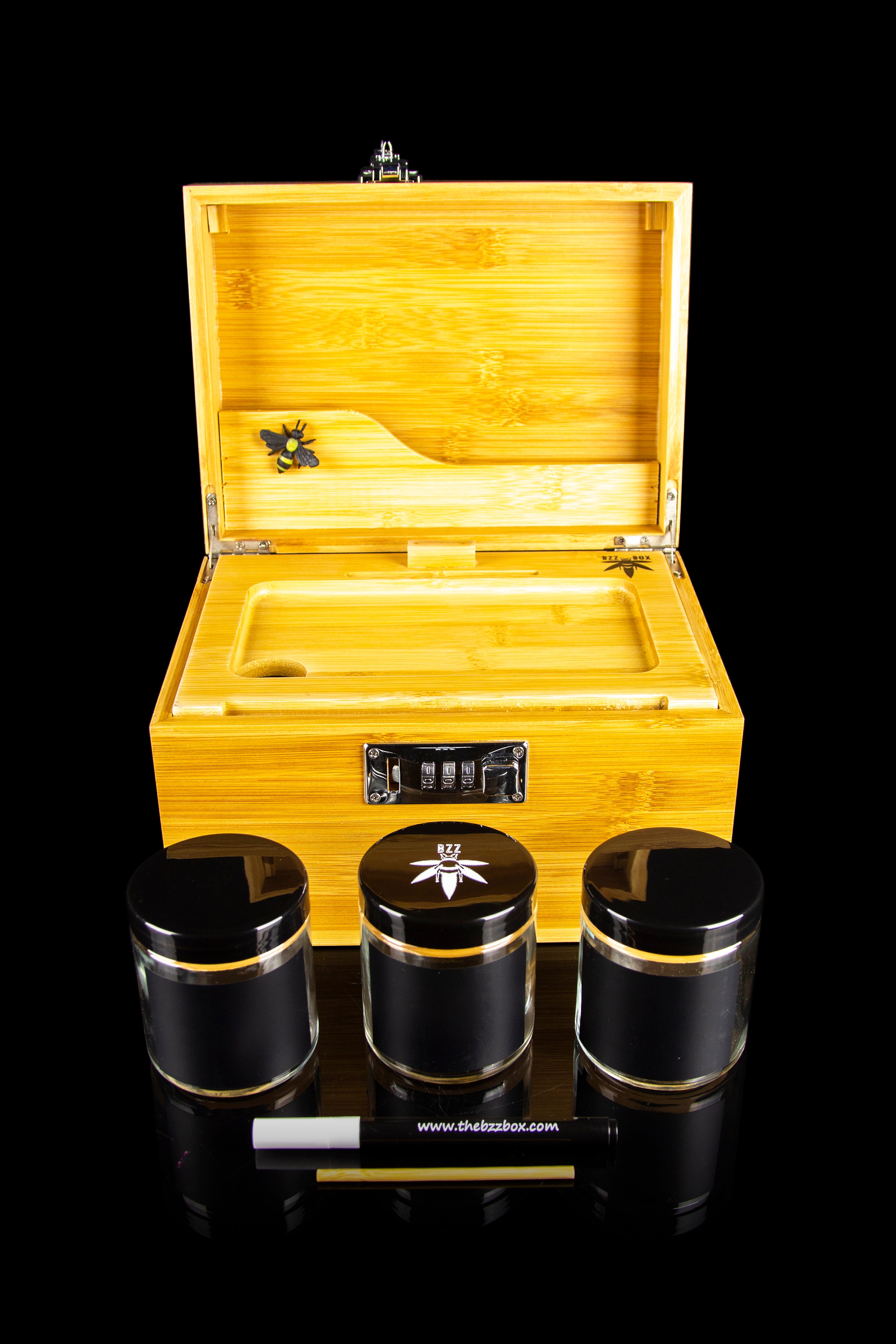 Wooden cannabis storage box with black airtight jars and a rolling paper, displayed on a black background.