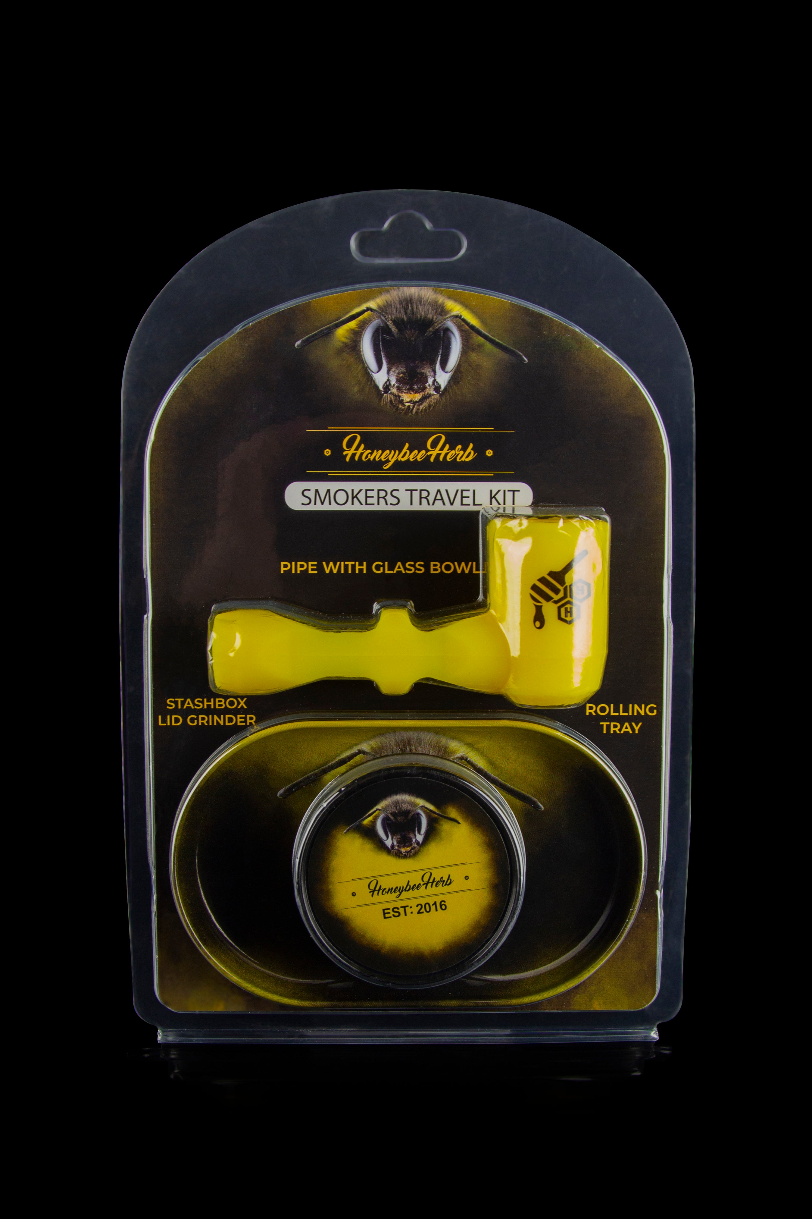 A clear, sealed travel kit containing a glass pipe with bowl, grinder, and rolling tray, branded with "Honeybee Herbs."