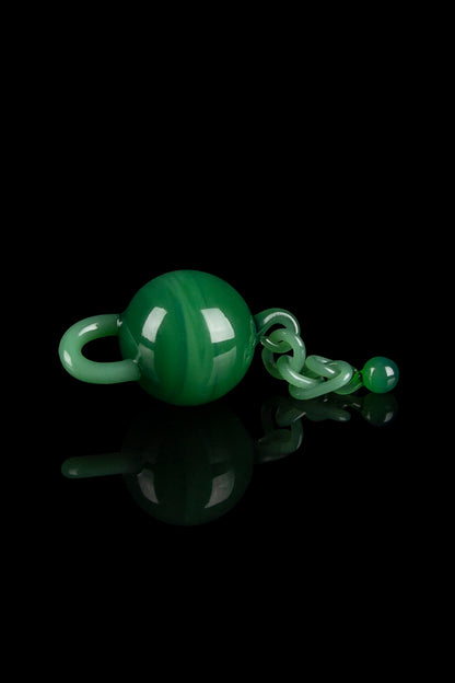 Dark green glass cannabis water pipe and accessories on a reflective black surface.