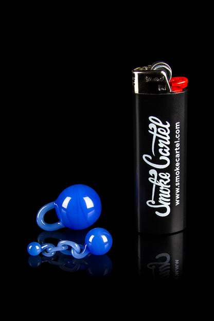 Blue glass marbles and a black lighter with “Smoke Cartel” branding on a reflective surface.