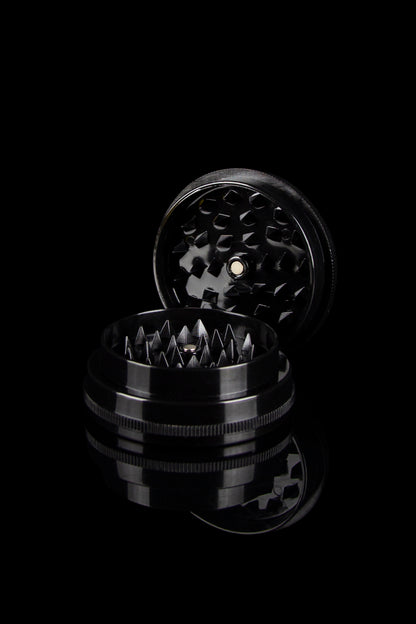 Black metal cannabis grinder disassembled, revealing tiered grinding components.