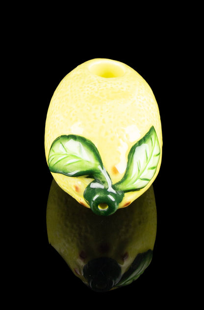 Yellow glass cannabis pipe with green leaf detailing and reflective surface.