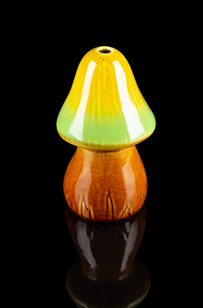Hand-blown glass mushroom-shaped water pipe with gradient orange and green coloring, isolated on black.