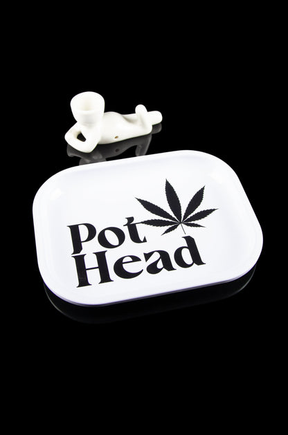 A white tin container labeled "Pot Head" with a cannabis leaf design and a small, white skull-shaped accessory on top, set against a black background.