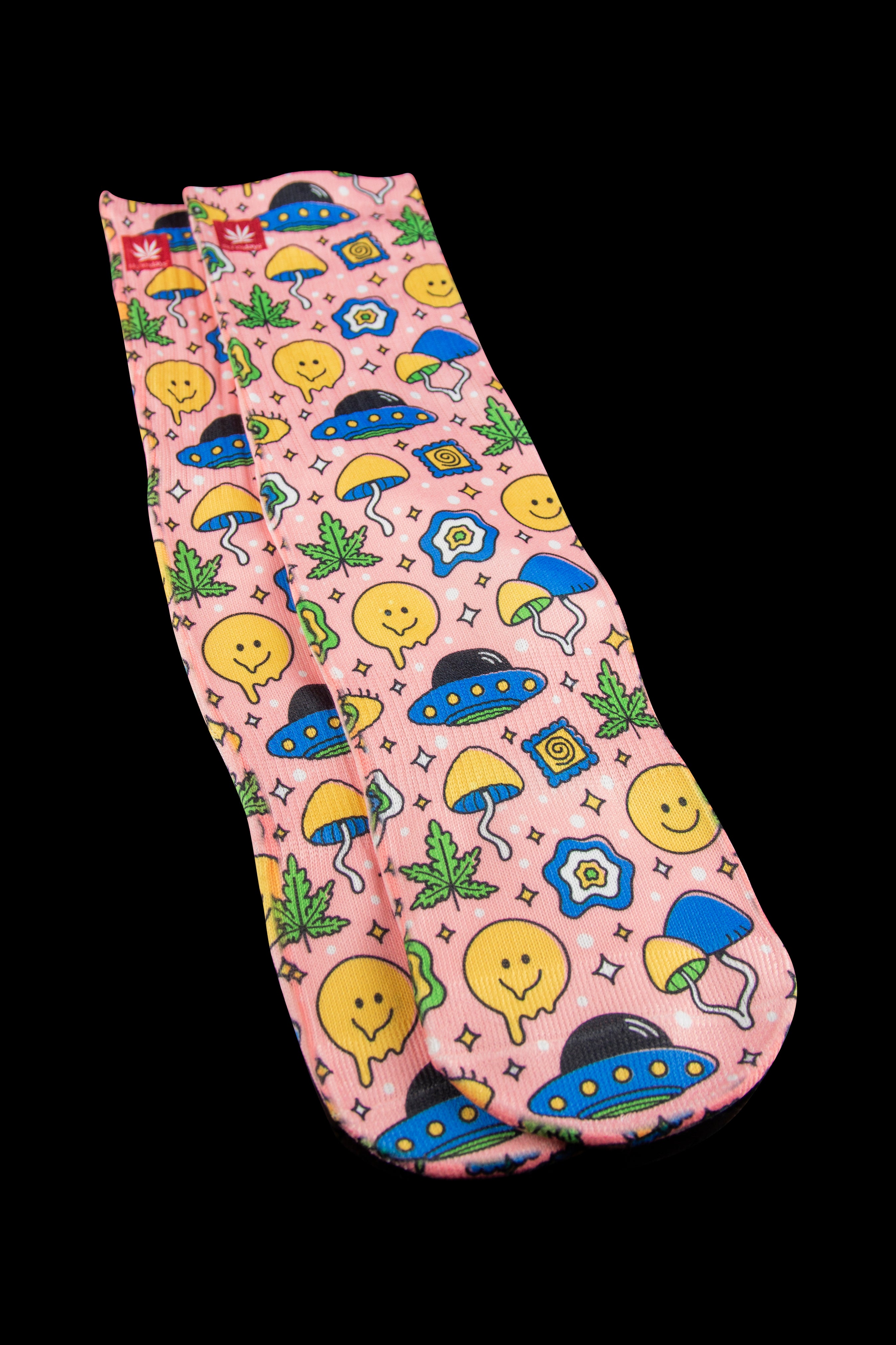 A peach-colored cannabis accessory bag with a whimsical pattern of smiling faces, mushrooms, cannabis leaves, and UFOs.