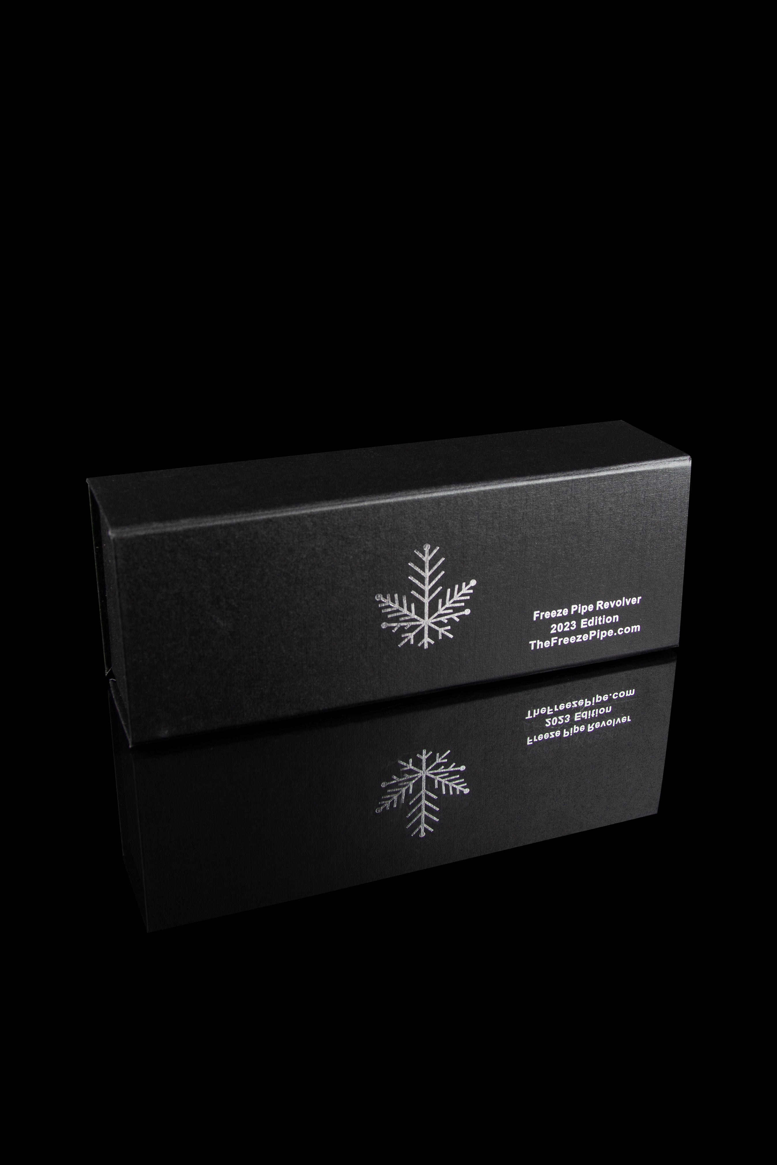 Black box for “Freeze Pipe Revolver 2023 Edition” with a snowflake design, reflecting on a glossy surface.