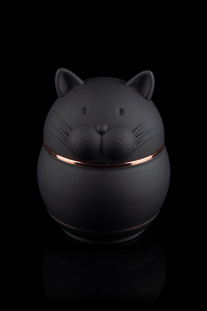 Black cat-shaped stash jar with copper trim, isolated on a black background.