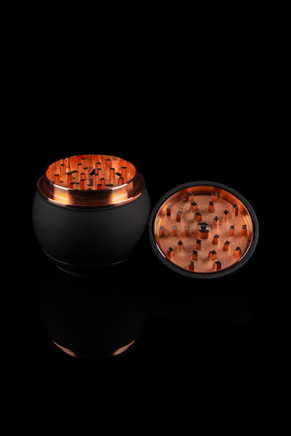 Black and copper grinder for cannabis, shown open with visible grinding teeth."
