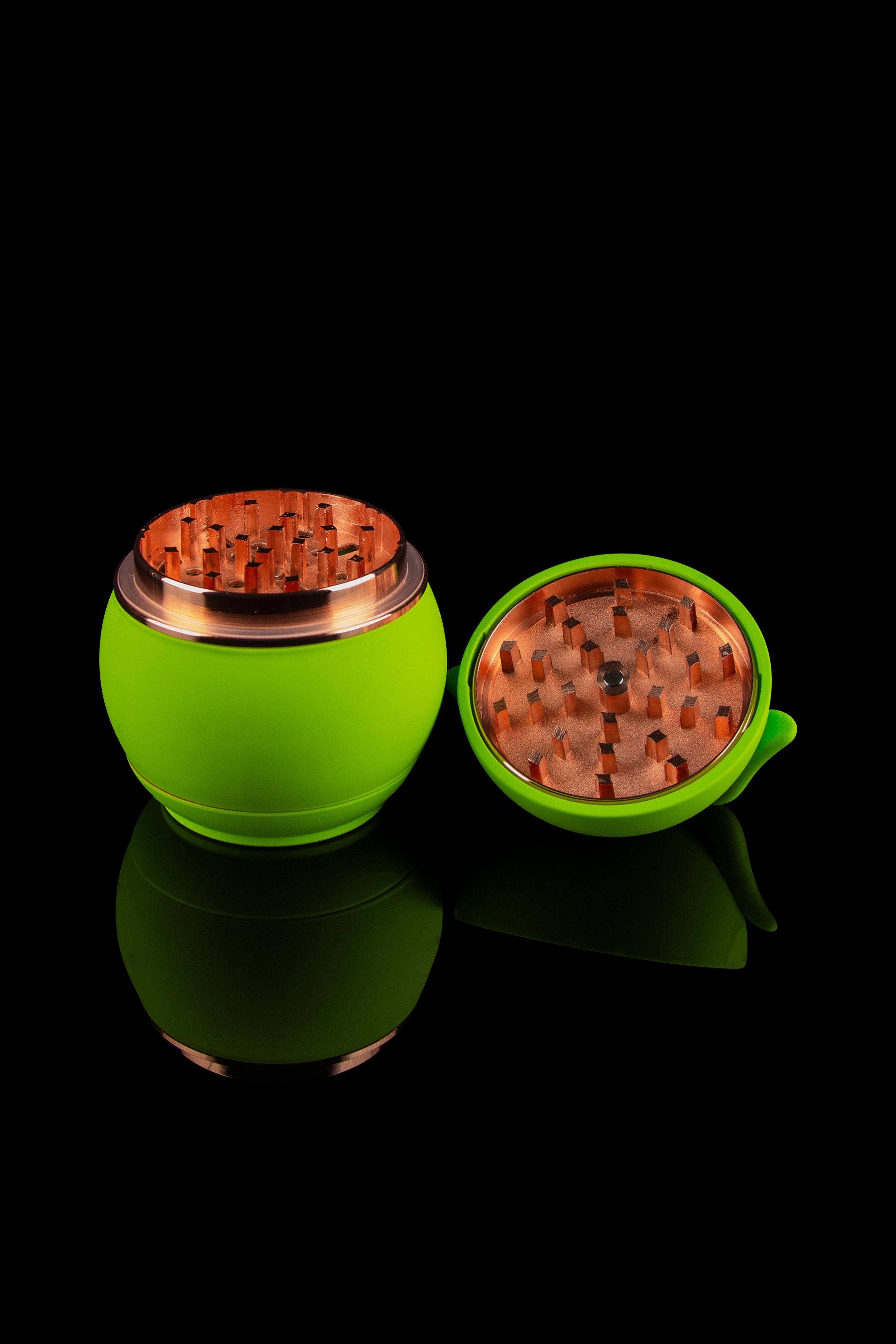 Green cannabis grinder with a gold interior, displayed open and closed on a reflective surface against a black background.