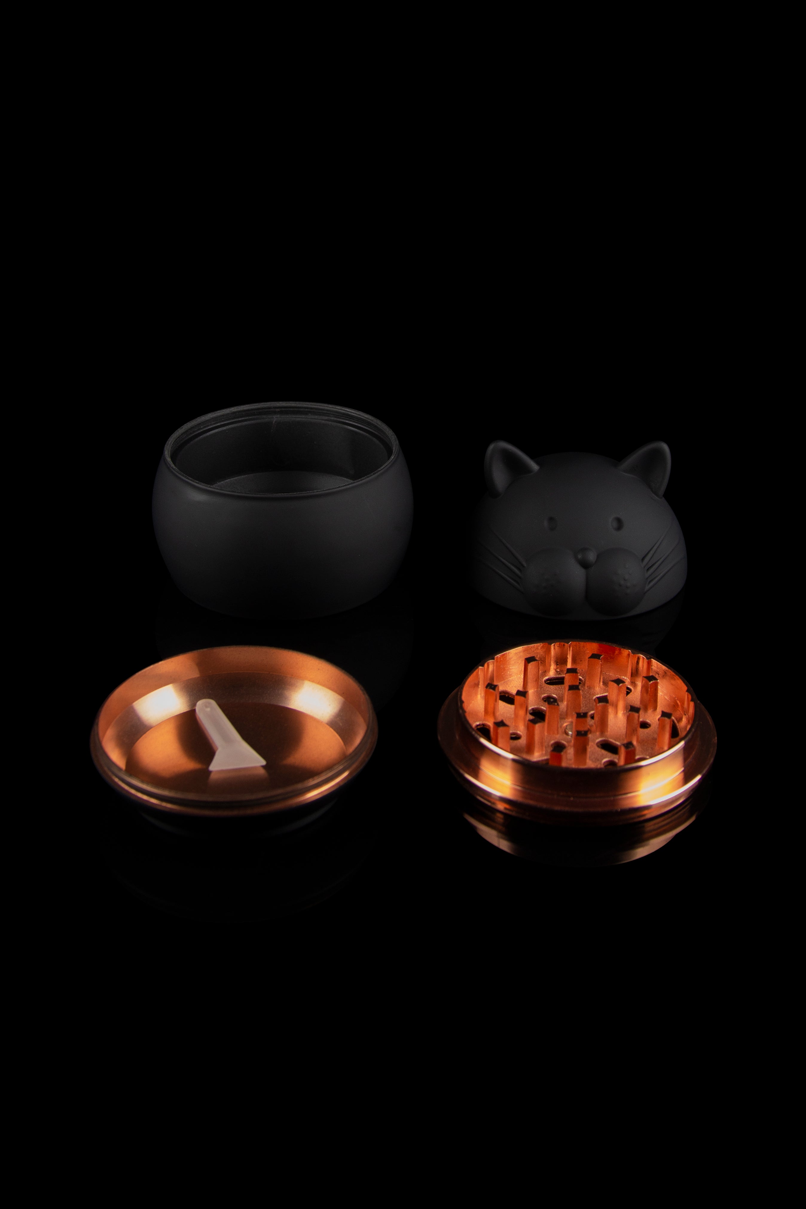 Black cat-shaped grinder with metallic grinding components displayed disassembled on a black background.