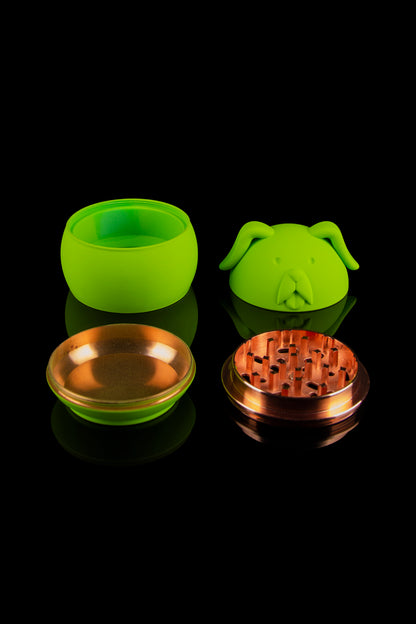 Bright green cannabis grinder shaped like a pig with disassembled components displayed on a reflective black surface.