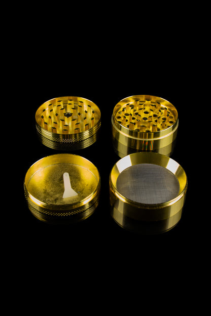 Gold cannabis grinder components disassembled on a black background.